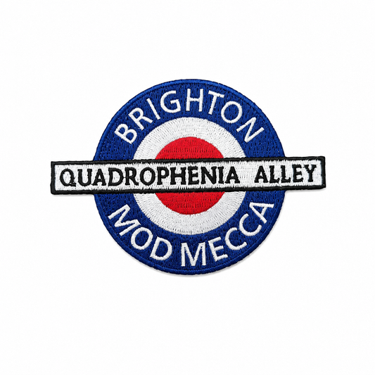 A circular embroidered patch featuring a blue border with white text reading 'BRIGHTON' at the top and 'MOD MECCA' at the bottom, surrounding a red, white, and blue target motif. A white horizontal banner across the center reads 'QUADROPHENIA ALLEY' in black letters.